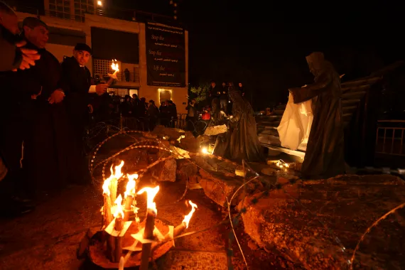 a small orange glowing fire lights up an outside nativity scene with barbed wire