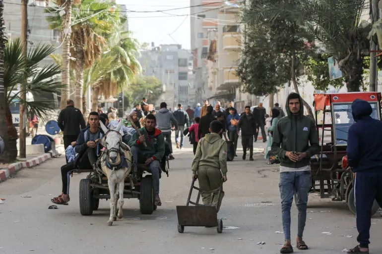 Displaced citizens carry their belongings on donkey carts, heading to Deir el-Balah along Salah al-Din Street. [Abdelhakim Abu Riash/Al Jazeera]
