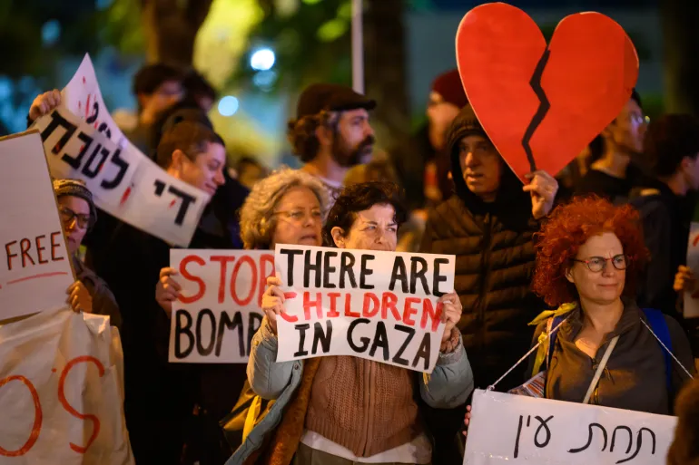 protestors hold a sign saying there are children in Gaza and a broken heart