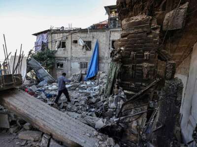 A man walks over the rubble of a destroyed home