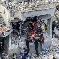 Men recover the body of a victim killed in the aftermath of an overnight Israeli strike at Maghazi refugee camp on December 25, 2023, amid ongoing battles between Israel and Hamas. (Photo by MAHMUD HAMS / AFP)