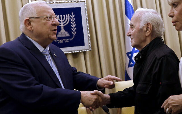 Former Israeli president Reuven Rivlin, left, shakes hands with French-Armenian singer Charles Aznavour on October 26, 2017 at the presidential compound in Jerusalem. (GALI TIBBON/AFP)
