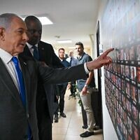 In this government handout photo, Prime Minister Benjamin Netanyahu shows US Defense Secretary Lloyd Austin pictures of hostages taken by Hamas in the Gaza-ruling terror group's October 7 onslaught, at the Defense Ministry in Tel Aviv on December 18, 2023. (Kobi Gideon/ GPO)