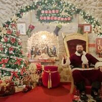 Issa Kassissieh dressed up as Santa Claus welcoming visitors inside 'Jerusalem's Santa House' in the Christian Quarter of the Old City, December 14, 2023. (Gianluca Pacchiani/Times of Israel)