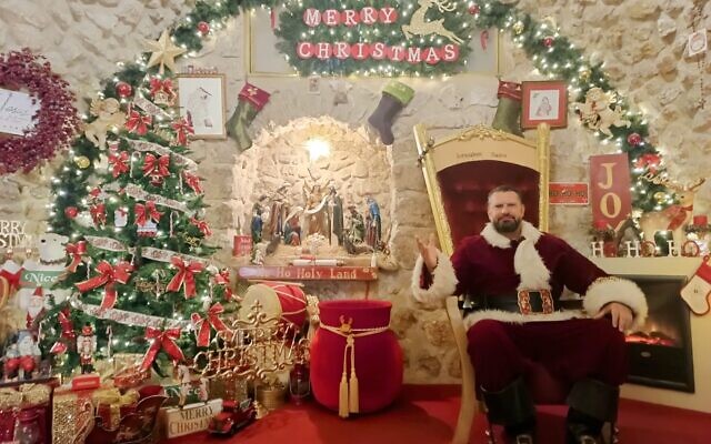 Issa Kassissieh dressed up as Santa Claus welcoming visitors inside 'Jerusalem's Santa House' in the Christian Quarter of the Old City, December 14, 2023. (Gianluca Pacchiani/Times of Israel)