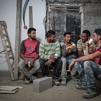 File: Palestinian construction workers from the West Bank village of Abadiya, during their coffee break at a house under renovation in the Jewish settlement of Alon, south of Jerusalem, on February 16, 2016. (Hadas Parush/Flash90)