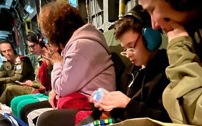 Ohad Munder, 9, on an IDF helicopter, unwraps a Rubik's Cube on his return to Israel on November 25, 2023, after being taken hostage by Hamas on October 7. His mother Ruti is alongside him (Israel Defense Forces)