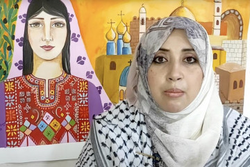 Woman in front of a painting of a Palestinian woman and buildings