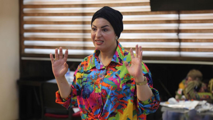 Woman wearing brightly coloured top and black hat 